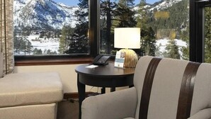 Una habitación con sofá, una mesita con lámpara y vistas a montañas nevadas a través de amplias ventanas.
