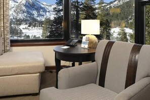 Una habitación con sofá, una mesita con lámpara y vistas a montañas nevadas a través de amplias ventanas.
