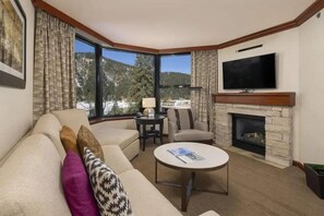 A living room with a sofa, armchairs, a coffee table, a fireplace, a television, and a large window with a mountain view. - Valley-View Suite in stunning Olympic Valley. Minutes away from Lake Tahoe and Truckee. (Olympic Valley)