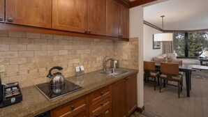 Una cocina con armarios de madera, encimera de granito, tetera y lavabo.
