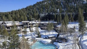 Un resort con piscina, paisaje nevado y colinas boscosas.