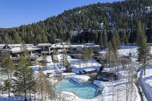 Un resort con piscina, paisaje nevado y colinas boscosas.