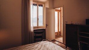 Een slaapkamer met een bed, een bureau, een stoel, een kledingkast en uitzicht op de omgeving.