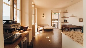 Een keuken met een koffieapparaat, houten meubels en een eethoek met een tafel en stoelen.