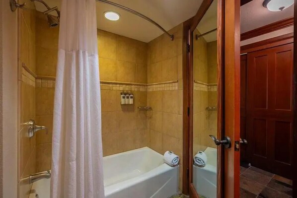 Une salle de bain avec une baignoire, une douche et un miroir.