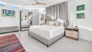 Um quarto moderno com uma cama grande, uma mesinha de cabeceira, um espelho e um ventilador de teto.