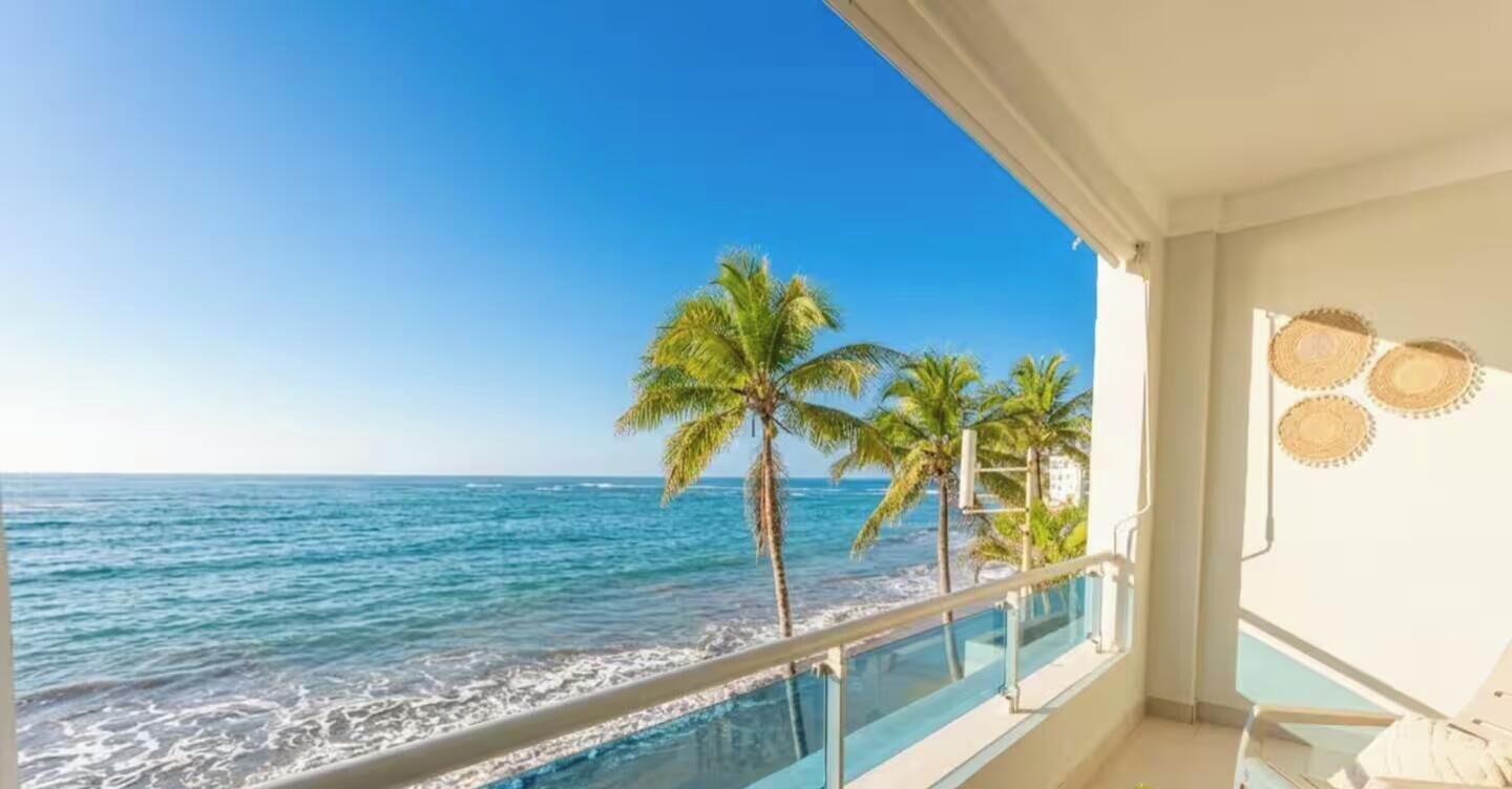 A balcony with a view of the ocean and palm trees.
