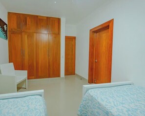 Ein Schlafzimmer mit Kleiderschrank, einem Bett und einem Sessel.