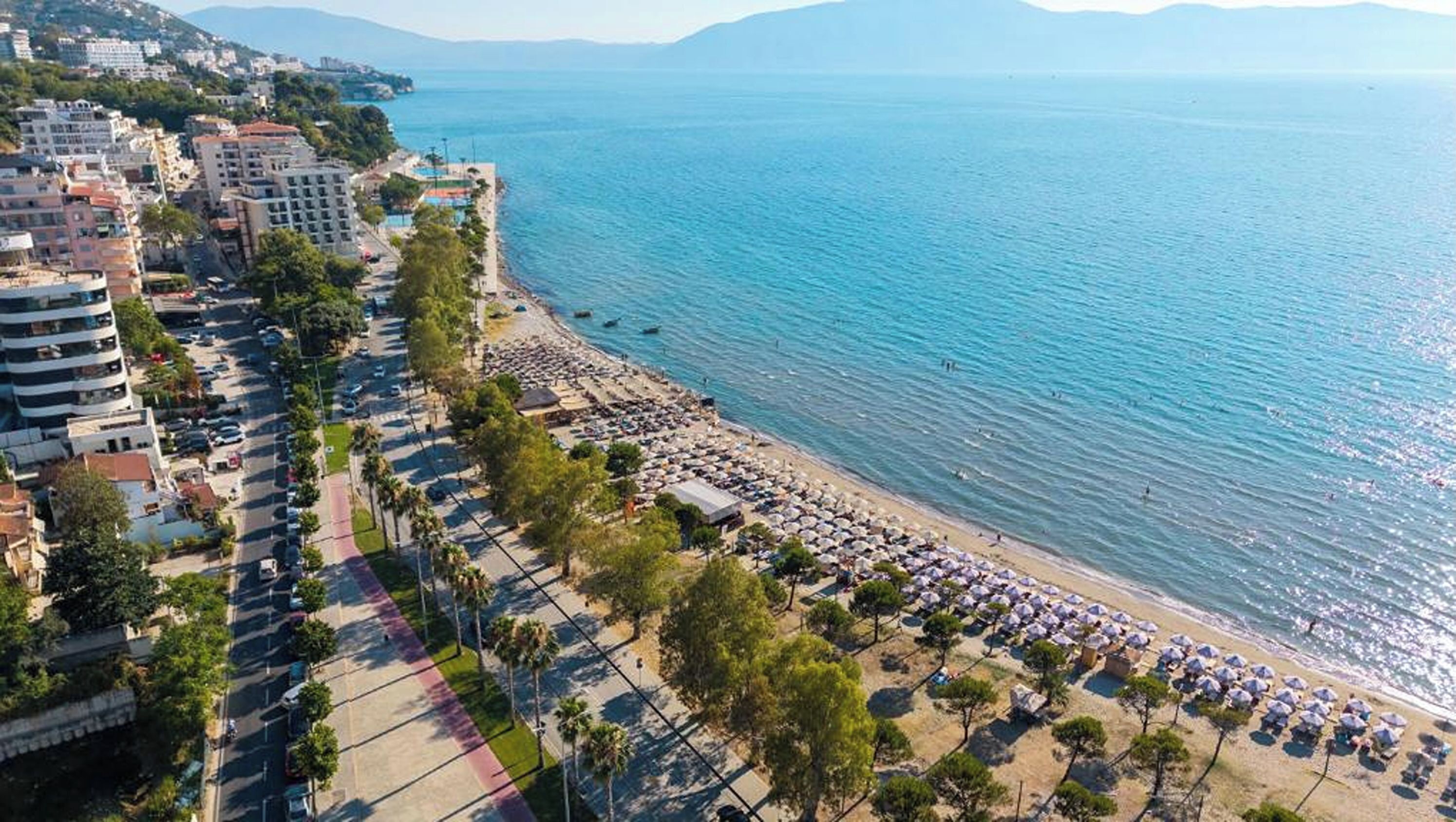 Vista aérea de una ciudad costera con playa, edificios y un mar azul y despejado.