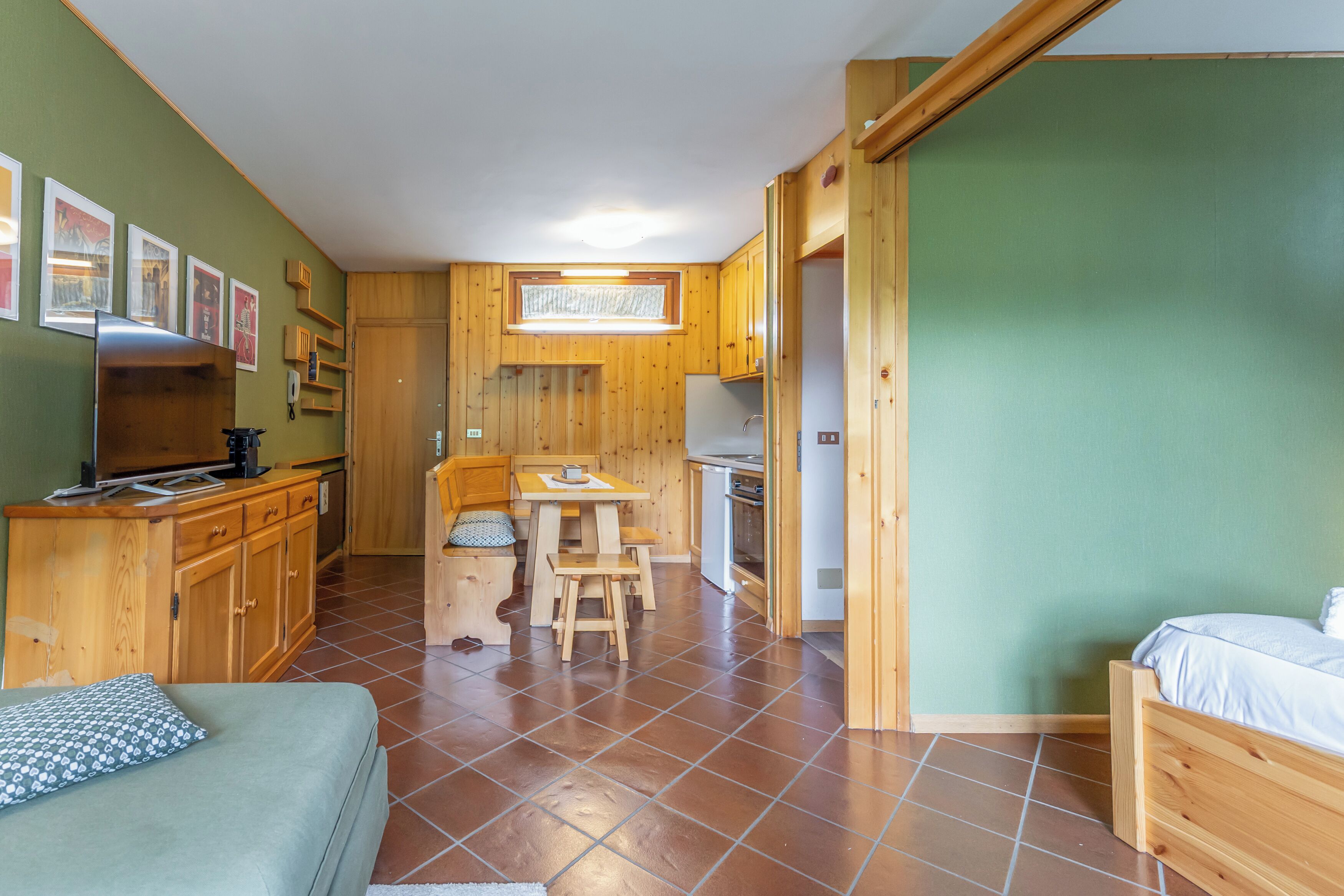 A compact room with a bed, a small kitchenette, a dining area, and a bathroom.