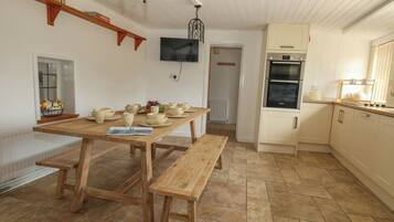 A kitchen with a wooden table, bench, and white cabinets.