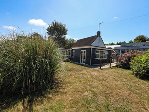 A small, single-story building with a sloped roof, a visible chimney, and a door. - Greenwich Cottage (Bridport)