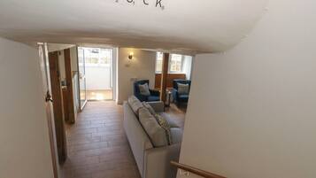 A staircase leading to a living area with a couch and two chairs, a wooden floor, and a door labeled 'DUCK'.
