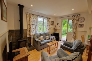A living room with a fireplace, two sofas, a coffee table, and a television. - Woodcutters near Bantham South Devon (Buckland Park, Bantham)