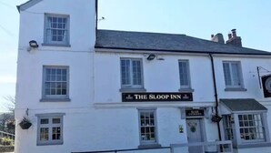 A white building with a sign reading 'The Sloop Inn' and a bar entrance.