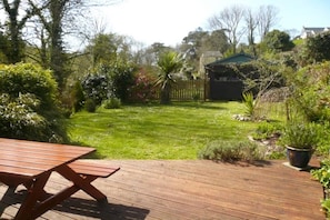 A wooden deck with a picnic table, a well-maintained lawn, and a fenced garden area. - Woodcutters near Bantham South Devon (Buckland Park, Bantham)