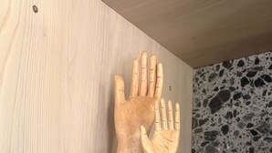 Eine Holzhandskulptur auf einem Regal.