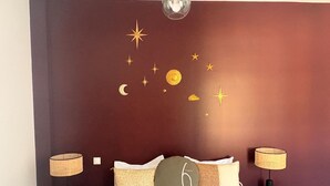 Ein Schlafzimmer mit einem Bett, zwei Nachttischen, Lampen und einer Wand mit Sternen- und Mondmotiven.