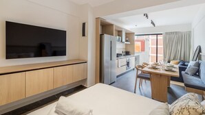 A modern hotel room with a large bed, a TV mounted on the wall, a dining area with a table and chairs, and a kitchenette. - Myla - Loft in Condesa (Mexico City)