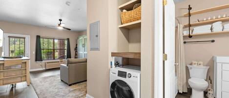 A laundry area with a washing machine, a drying rack, and shelves with towels.