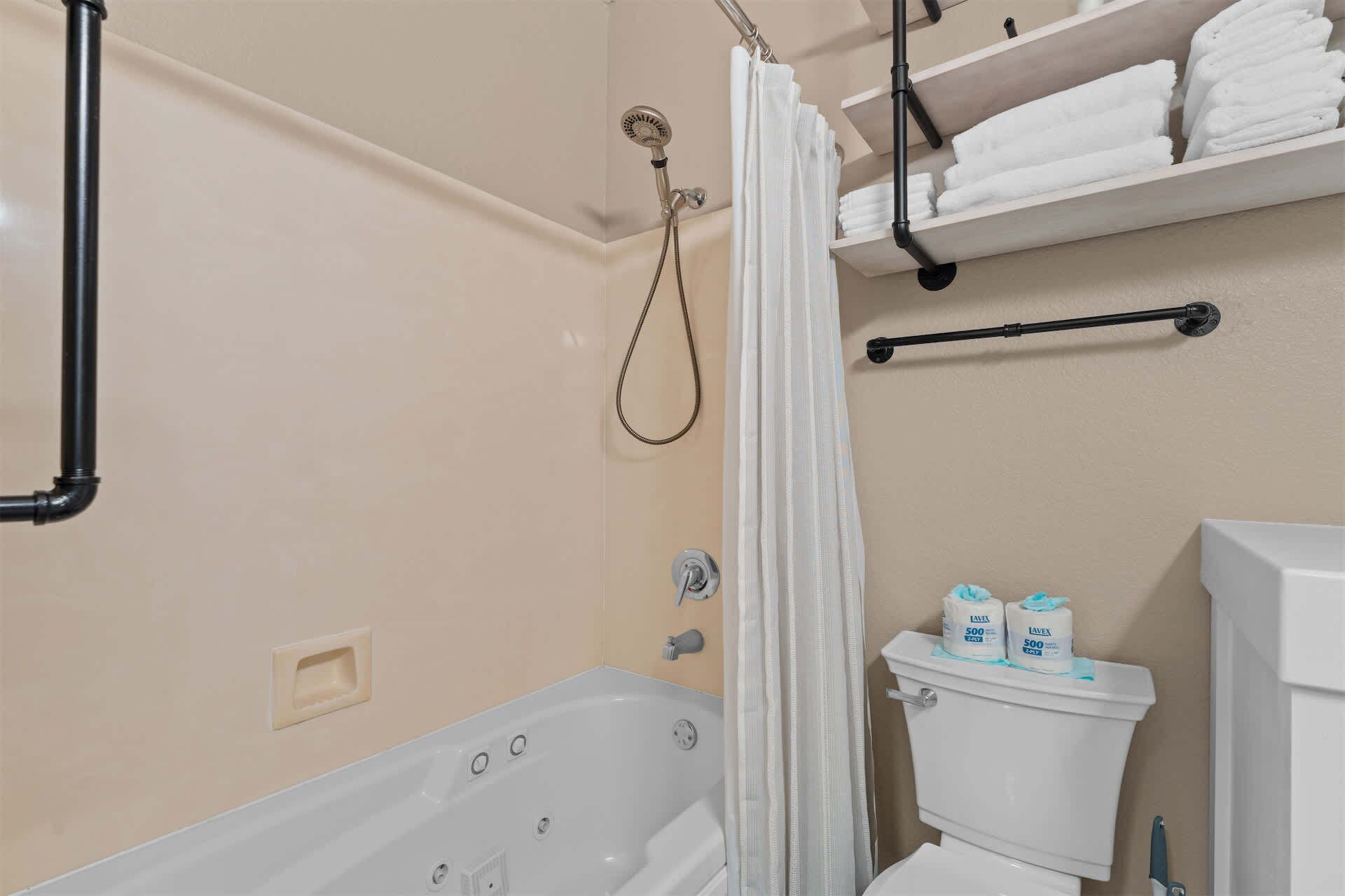 A bathroom with a bathtub, toilet, shower, and towel rack.