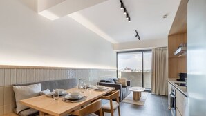 En modern lägenhet med matplats, soffa, kök och en balkong med utsikt över staden.