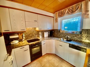 A kitchen with white cabinets, a granite countertop, a built-in oven, and a window with a decorative grid pattern. - Chalet Kristall # 6-bed apartment, Dusche, WC 6-bed apartment, Dusche, WC by Interhome (Albinen)