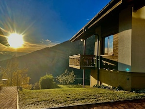 A modern building with a balcony, surrounded by a grassy area and mountains. - Chalet Kristall # 6-bed apartment, Dusche, WC 6-bed apartment, Dusche, WC by Interhome (Albinen)