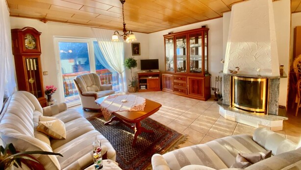 Ein Wohnzimmer mit Kamin, Holzbalkendecke und einer Sofagarnitur.