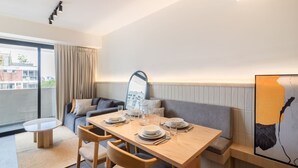 Ein modernes Hotelzimmer mit Essbereich, einer Couch, einem kleinen Tisch und einem großen Fenster.