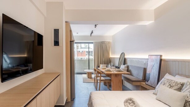 Ein Hotelzimmer mit Bett, Schreibtisch, Stuhl, Fernseher und Blick ins Freie.