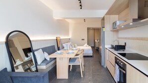 Ein stilvolles, helles Zimmer mit Esstisch, Sofa und Küchenzeile.
