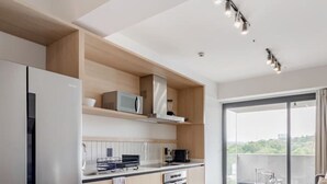 A modern kitchen with a dining area, built-in appliances, and a view of greenery. - Myla - 1BR Loft Plus in Condesa with balcony (Mexico City)