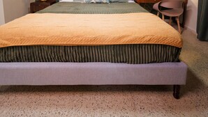 Ein Schlafzimmer mit einem großen Bett, einem Schreibtisch, einem Stuhl, einem Deckenventilator und einem wandmontierten Spiegel.