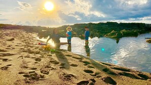 Eine Strandansicht mit Fußabdrücken im Sand und einem Gewässer.