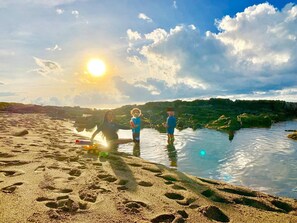 Eine Strandansicht mit Fußabdrücken im Sand und einem Gewässer.