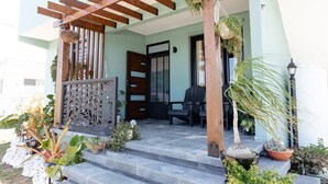 Ein Haus mit einer Holzpergola, einer schwarzen Tür und Topfpflanzen an der Veranda.