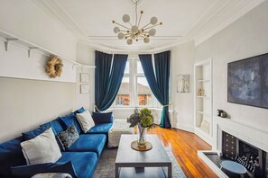 Un salon moderne avec un canapé bleu, une table basse et une cheminée.