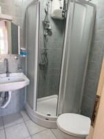 A shower enclosure with a glass door, a sink, and a toilet.