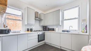Een moderne keuken met witte kastjes, een ingebouwde oven en een gasfornuis.