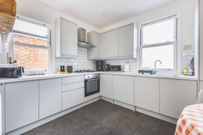 A modern kitchen with white cabinetry, a built-in oven, and a gas stove. - Spacious 2BDR 2BA near Shepherds Bush Oasis (Greater London)