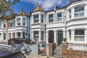 A row of white terraced houses with bay windows, a brick gate, and a car parked in front. - Spacious 2BDR 2BA near Shepherds Bush Oasis (Greater London)