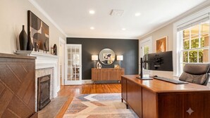 A modern living room with a fireplace, a wooden desk, and a comfortable seating area. - Main House + Studio Cottage • 2 Acres (Greer)