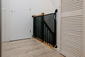 Una habitación con una puerta blanca, una reja de seguridad negra y suelo de madera.