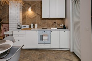 Cozinha moderna com armários brancos, forno embutido e painel de backsplash em padrão herringbone.