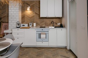 Una cocina moderna con armarios blancos, horno empotrado y salpicadero con motivo de espiga.