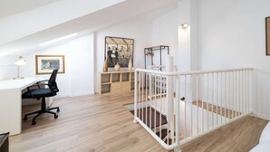 Et moderne loftværelse med skrivebord, kontorstol og billedkunst på væggene.
