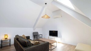 En moderne loftlejlighed med sofa, stole, sofabord, TV og ovenlys.