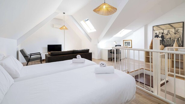 Et moderne hotelværelse med en stor seng, et skrivebord, en stol og et fjernsyn.