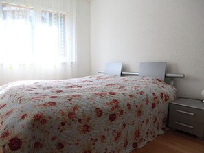 A bedroom with a bed, bedside tables, and a window with curtains. - Edelweiss E 21 # 4-bed apartment, Dusche, WC 4-Bettwohnung, Dusche, WC by Interhome (Leukerbad)